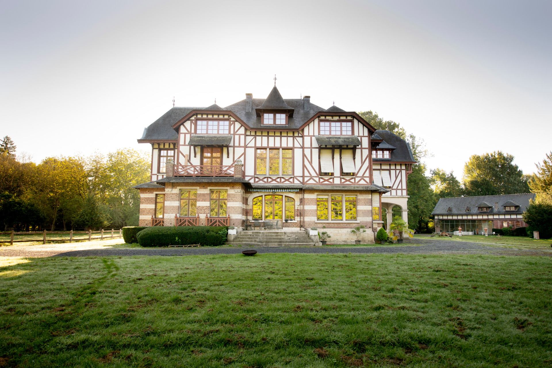 Domaine de la Nèle — the half-timbered château across the front lawn in early-morning sun